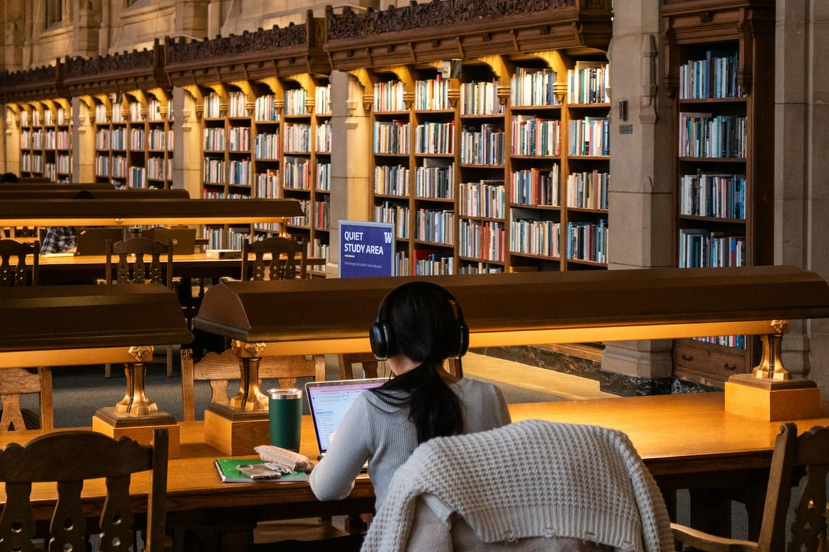 A researcher studying with a laptop in a grand university library